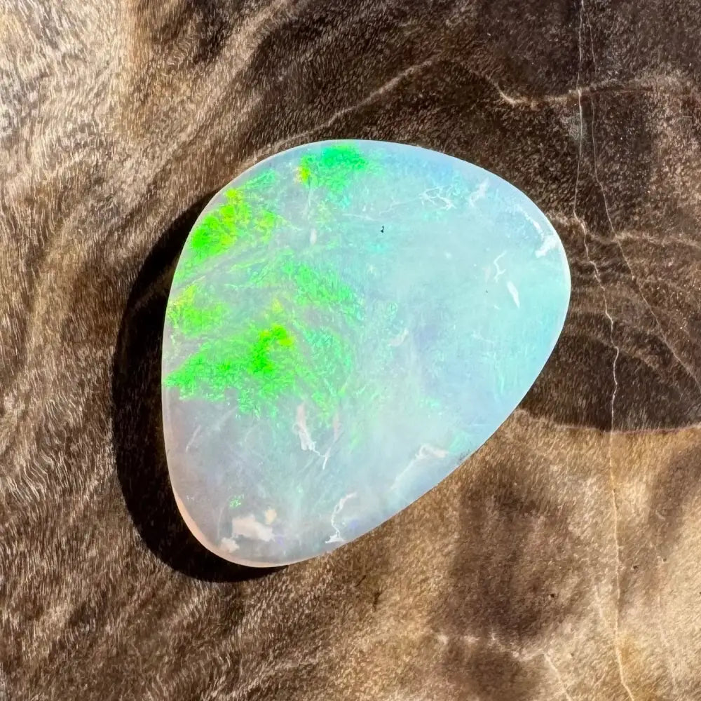 Iridescent opal gemstone with green inclusions.