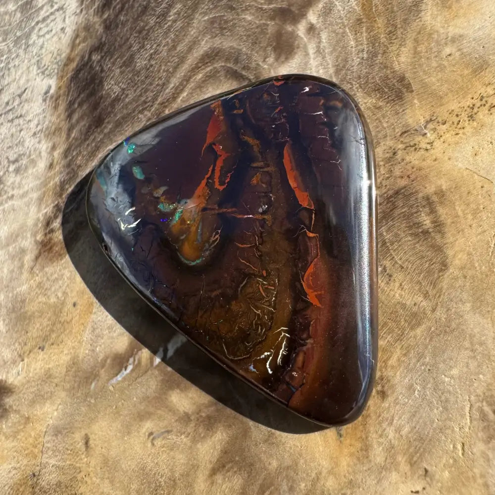 Polished dark opal with red and green flashes.