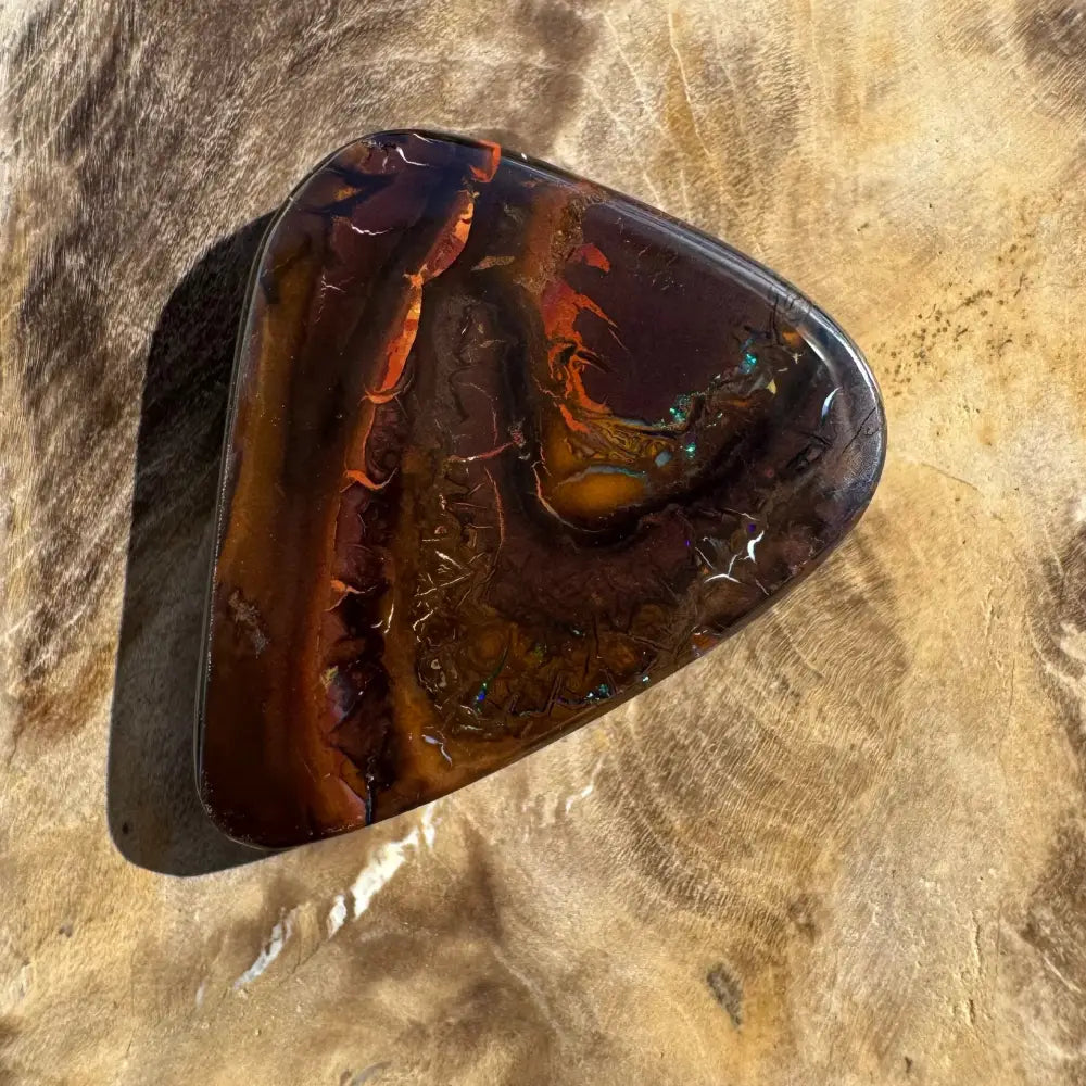 Polished triangular opal with brown and orange hues.