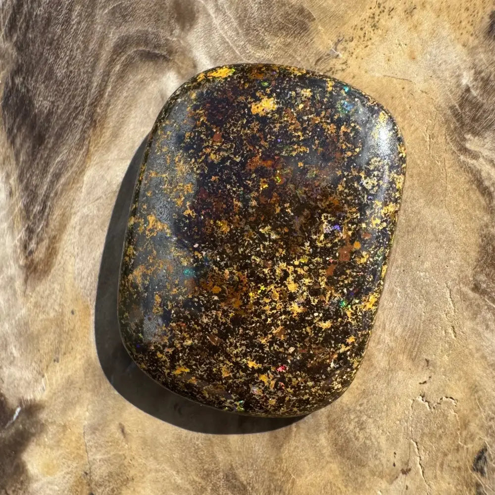 Polished black opal with gold flecks.