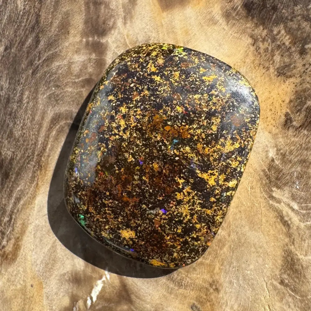 Polished black opal with gold flecks.