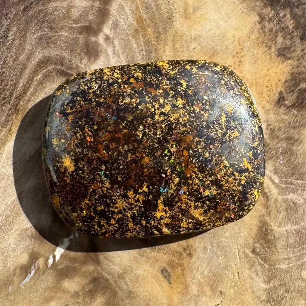 Polished black opal with gold flecks.