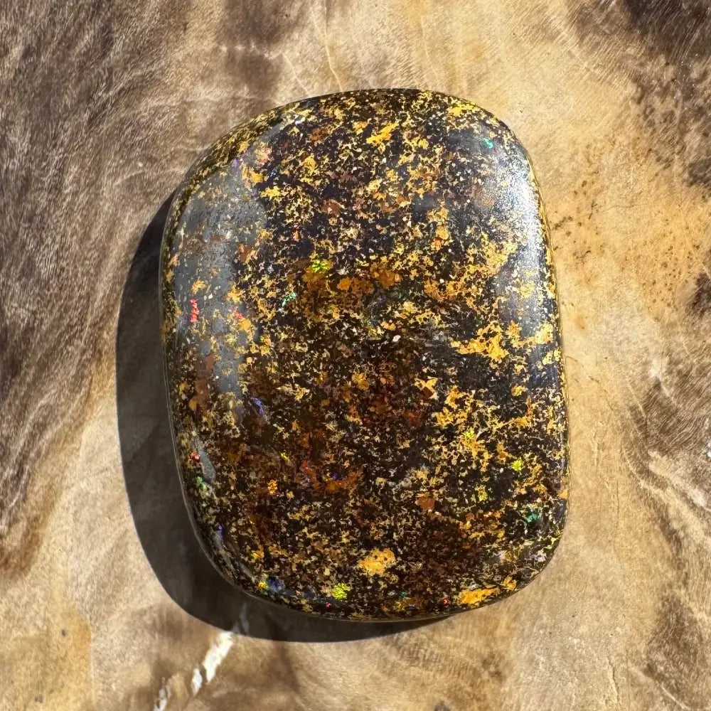 Polished black opal with gold flecks.