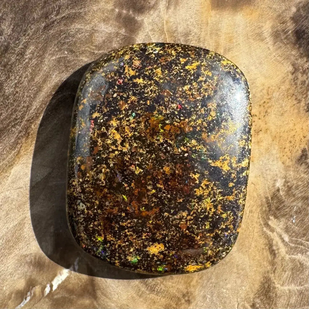 Polished black opal with golden flecks.