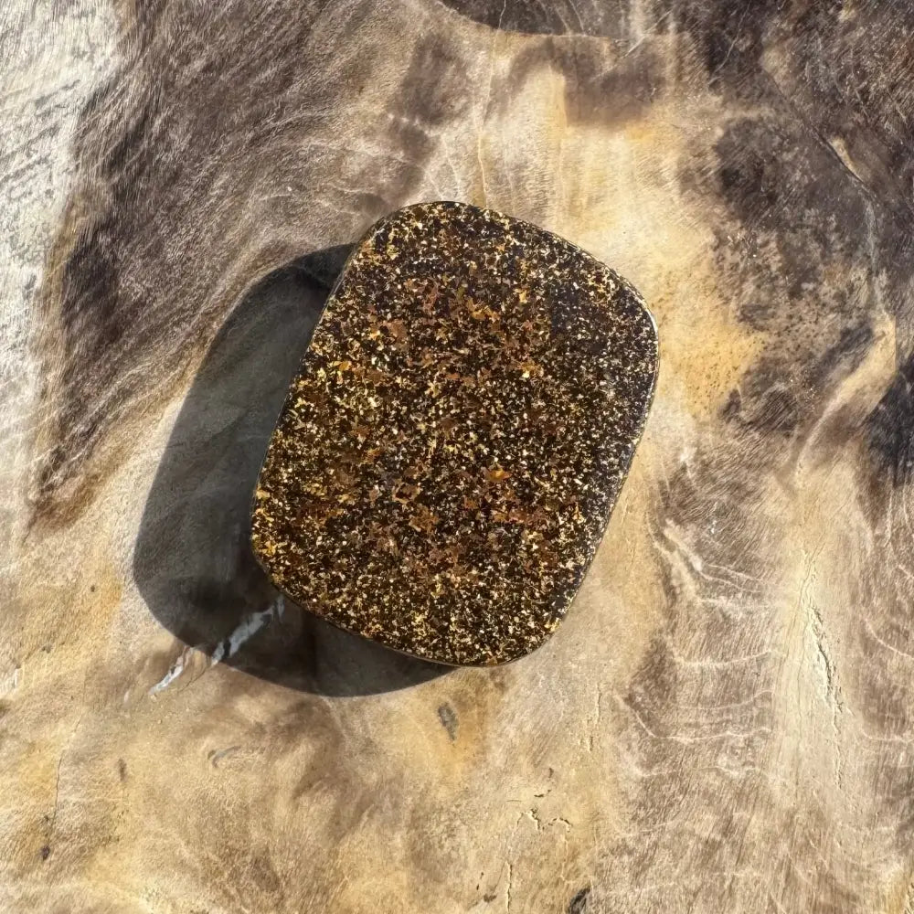 Rectangular, speckled, brown and gold stone.