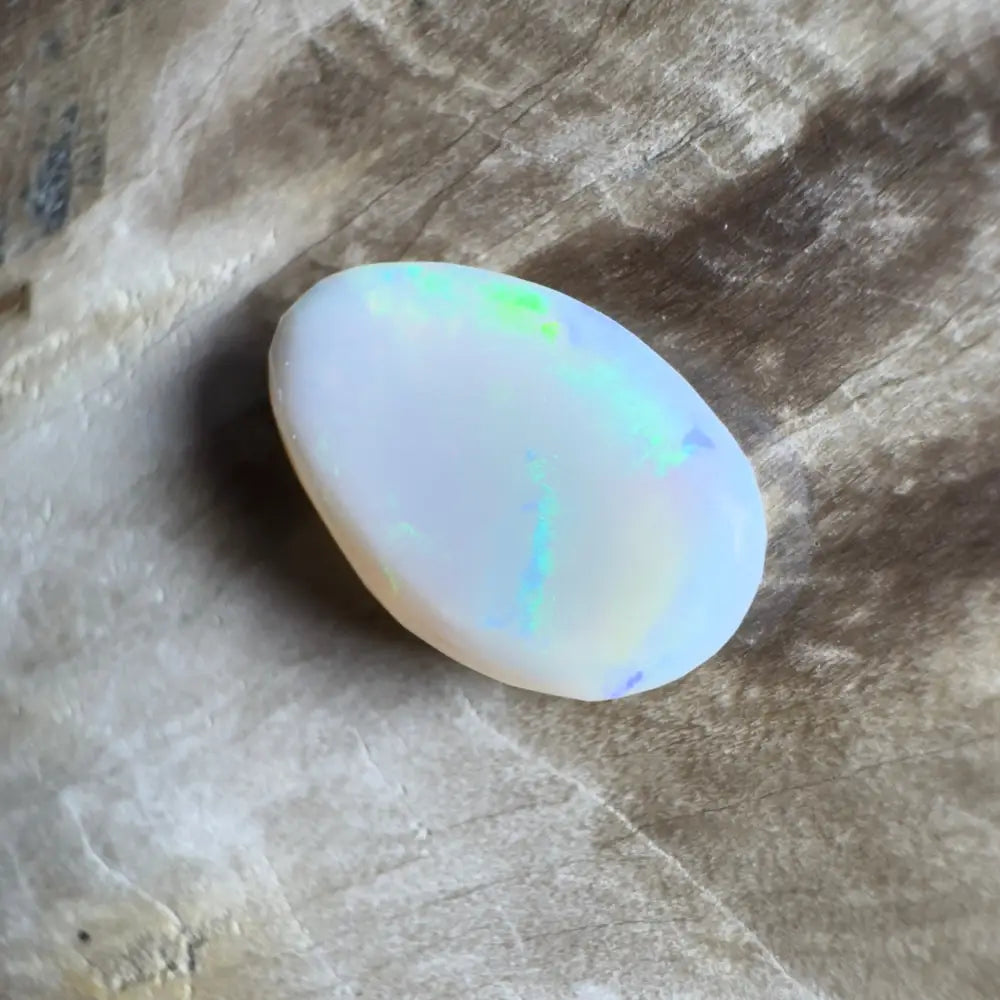 Oval white opal with iridescent flashes.