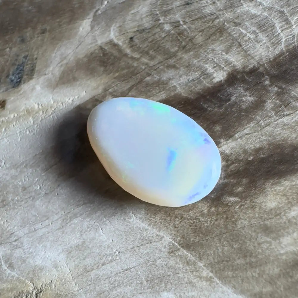 Oval white opal with iridescent flashes.