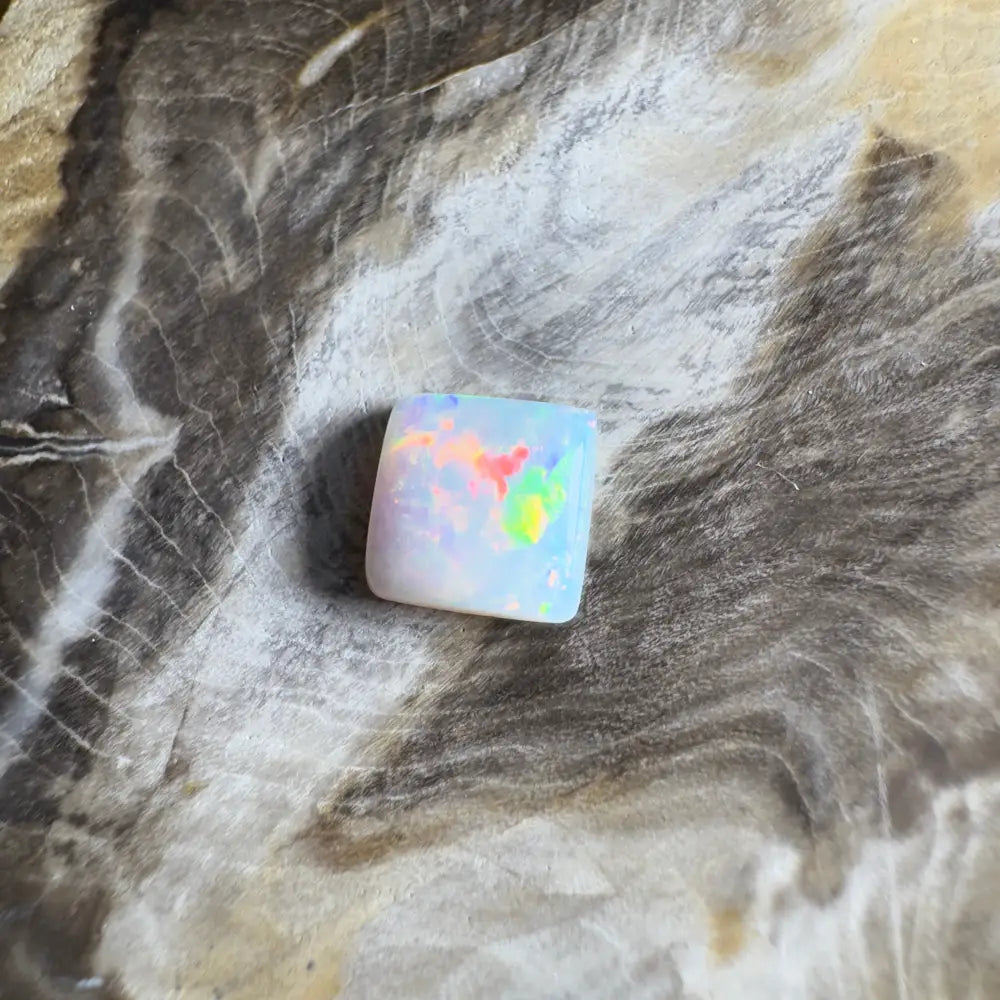 Square opal gemstone with rainbow flashes.