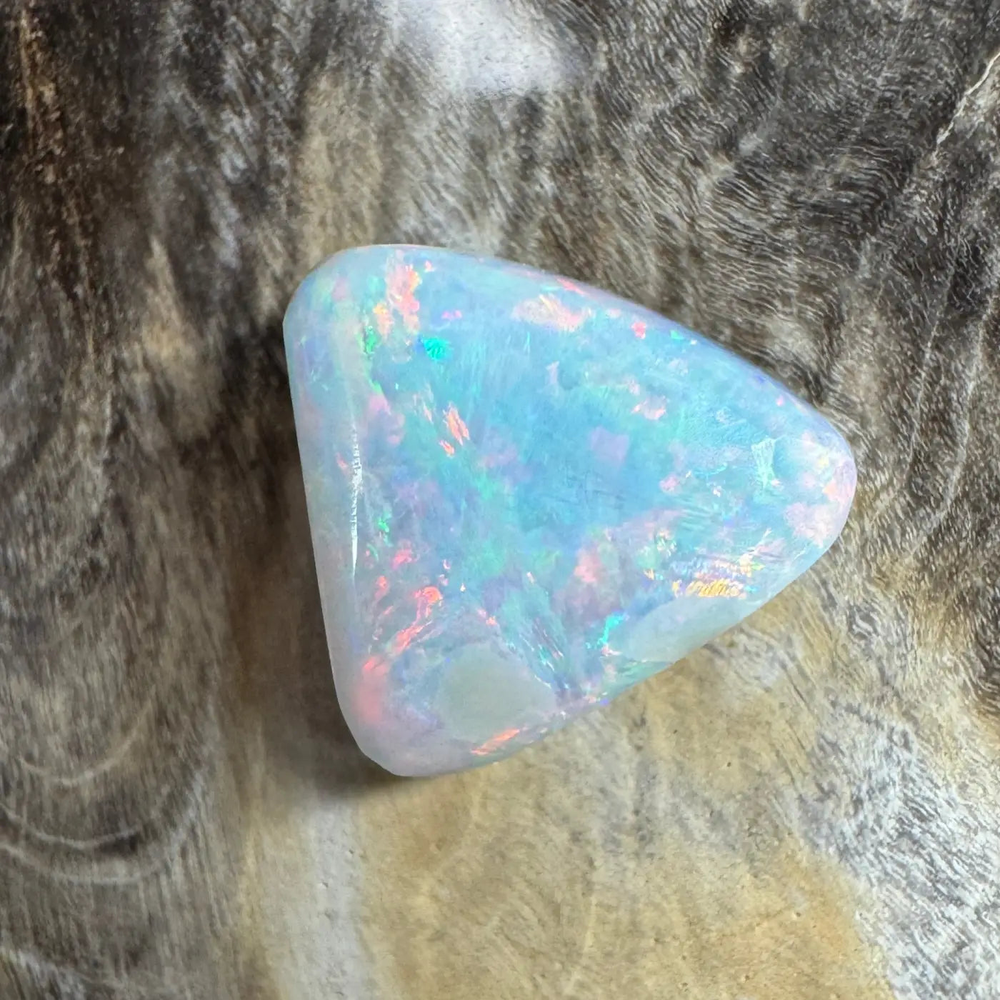 Iridescent triangular Lightning Ridge semi-black opal gemstone in a product listing