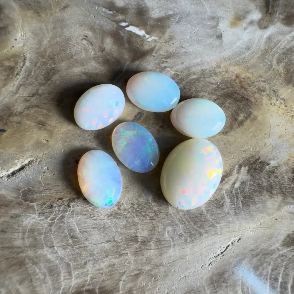 Six oval opals with iridescent flashes.