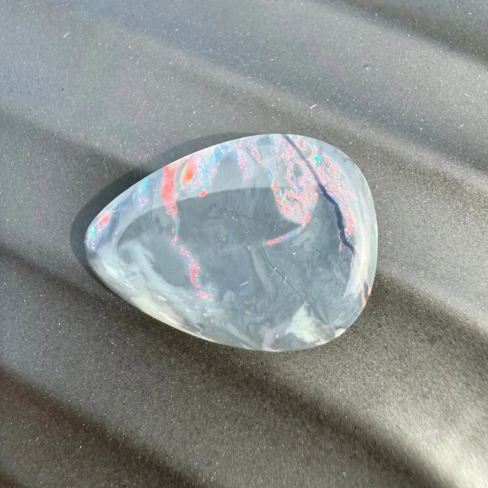 Polished teardrop-shaped Lightning Ridge semi-black opal with red and blue inclusions