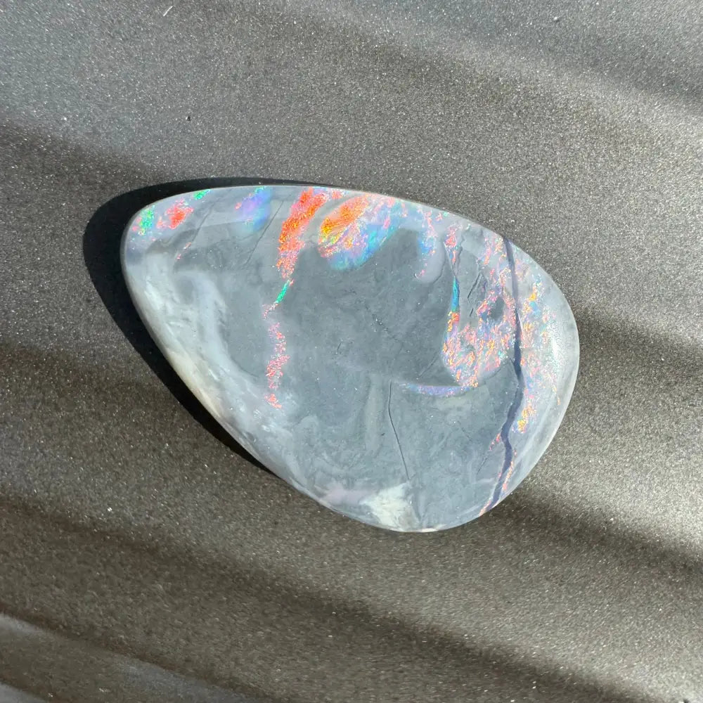 Iridescent black opal cabochon displayed in 5.7 carat Hand-Cut Solid Lightning Ridge Semi Black Opal