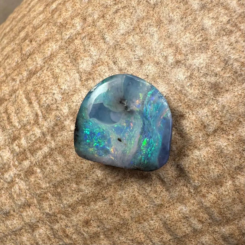 Iridescent blue-green Queensland Boulder Opal cabochon showcasing vibrant, natural colors