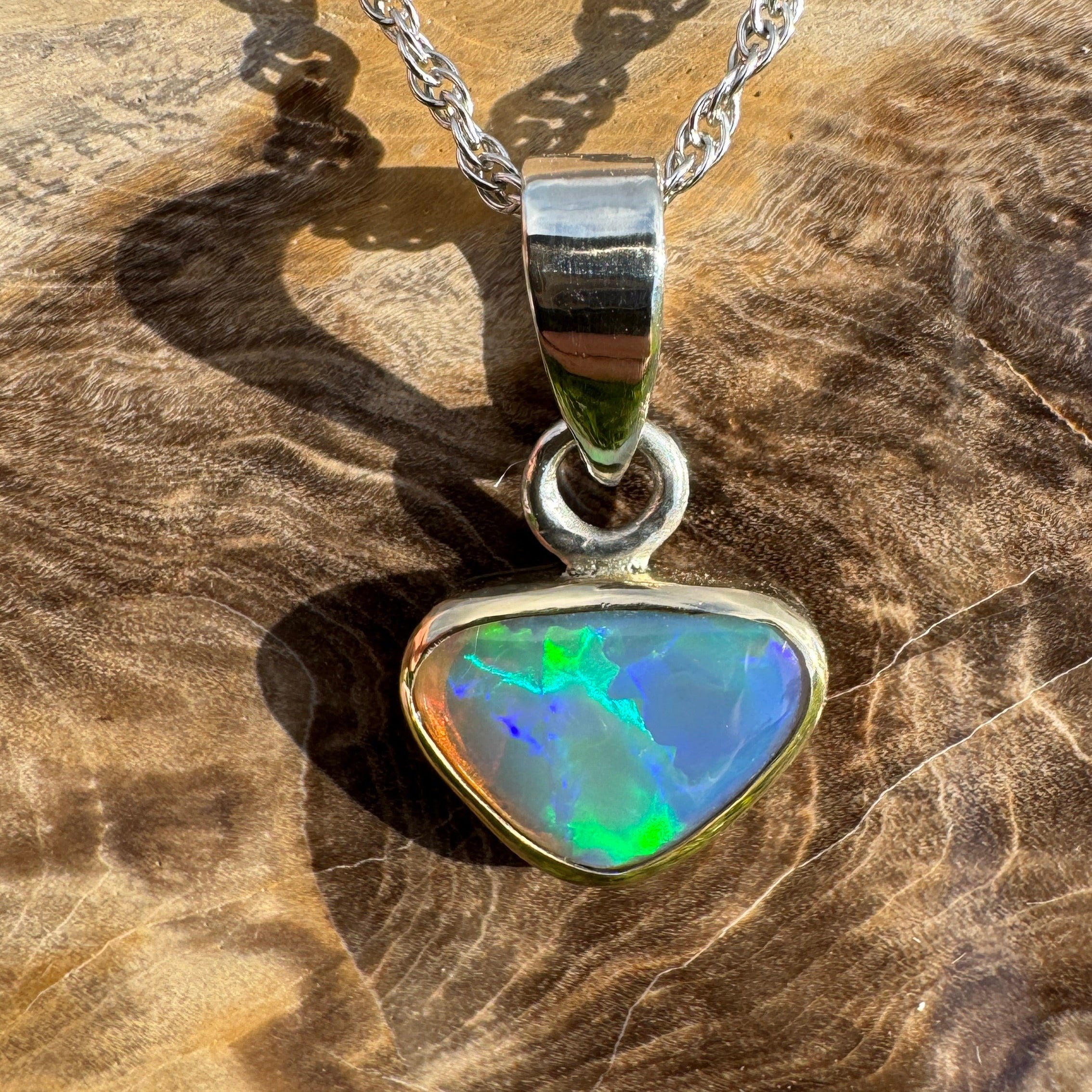Opal pendant on a silver chain against a wooden background