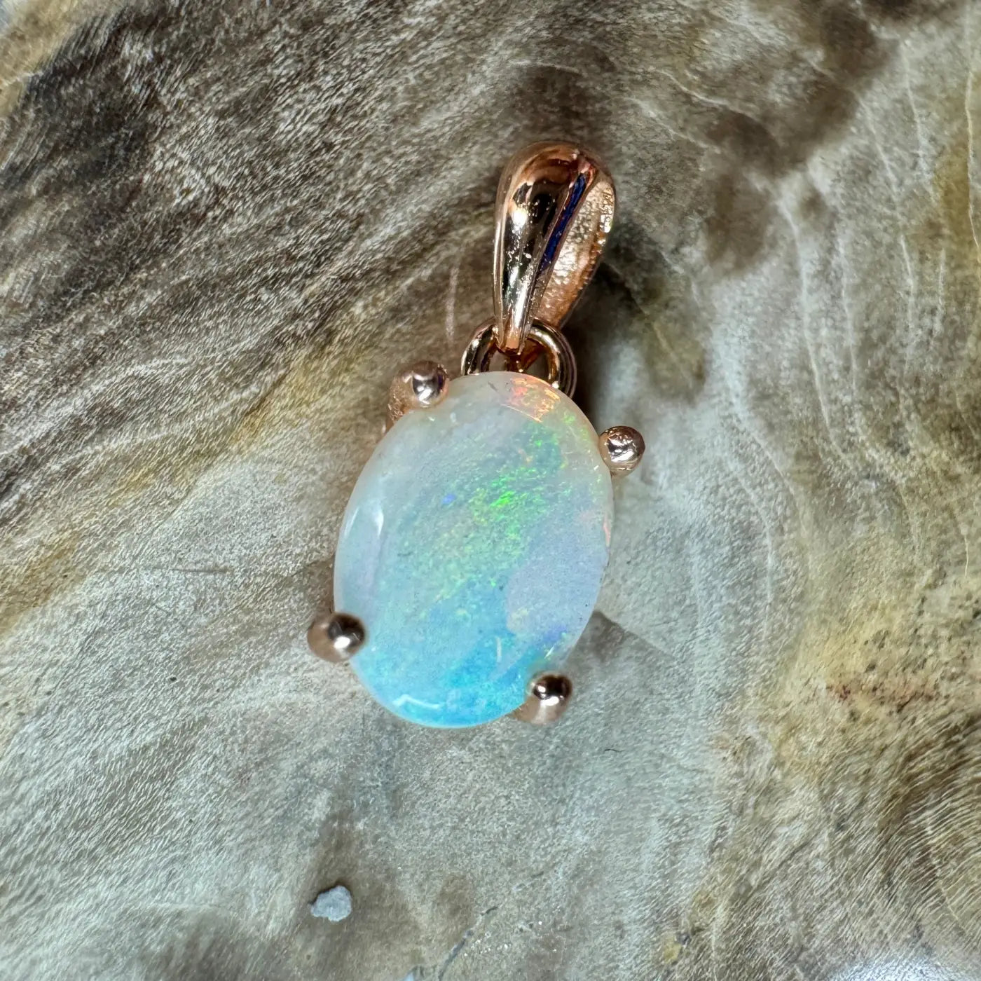 Oval Blue Water Cove Opal pendant with rose gold prongs and bail on sterling silver base