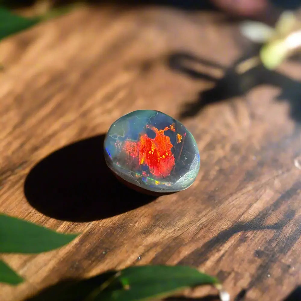 Polished Lightning Ridge Black Opal with red and blue iridescence in a 0.9 carat hand-cut product
