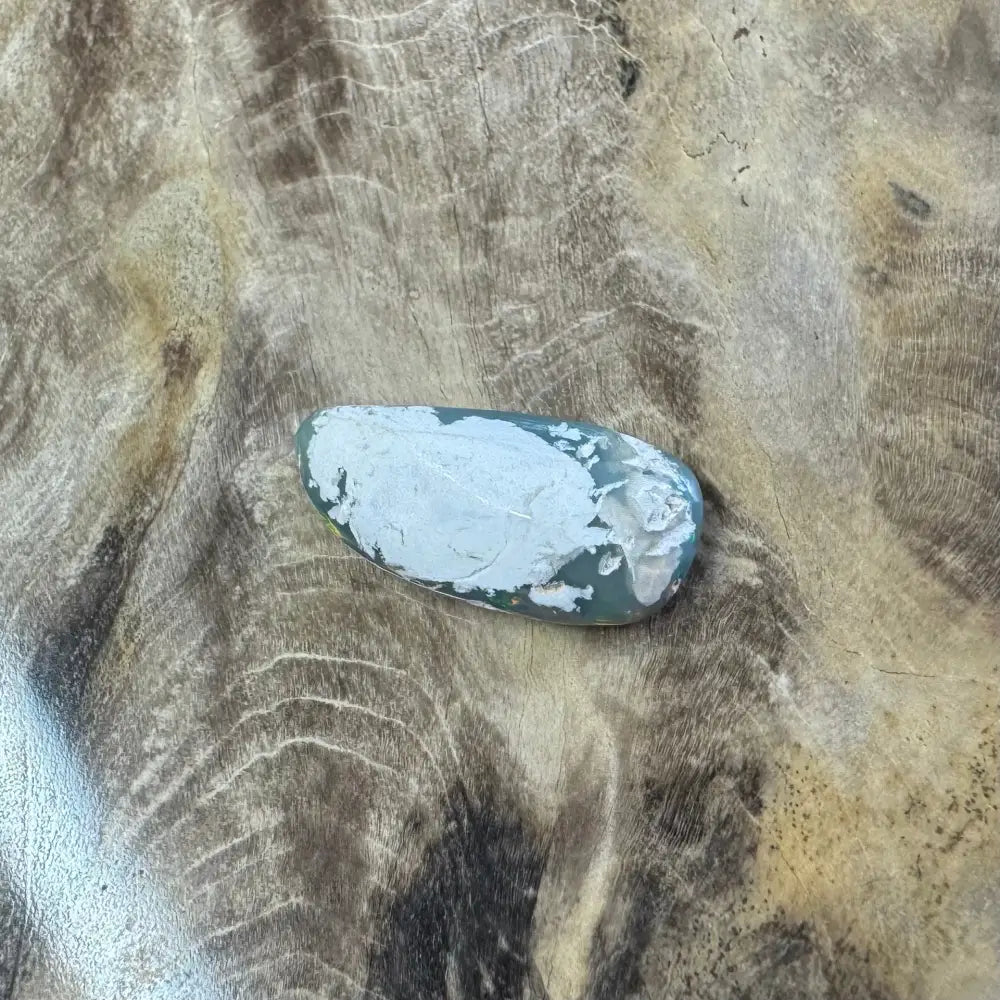 Polished green Lightning Ridge Opal with white putty used for setting in the jewelry piece