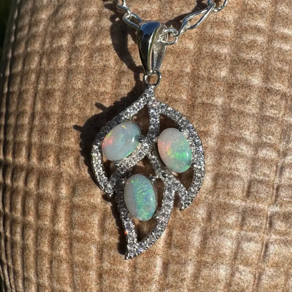 Silver leaf pendant featuring three opals, diamond accents, and handcrafted sterling silver