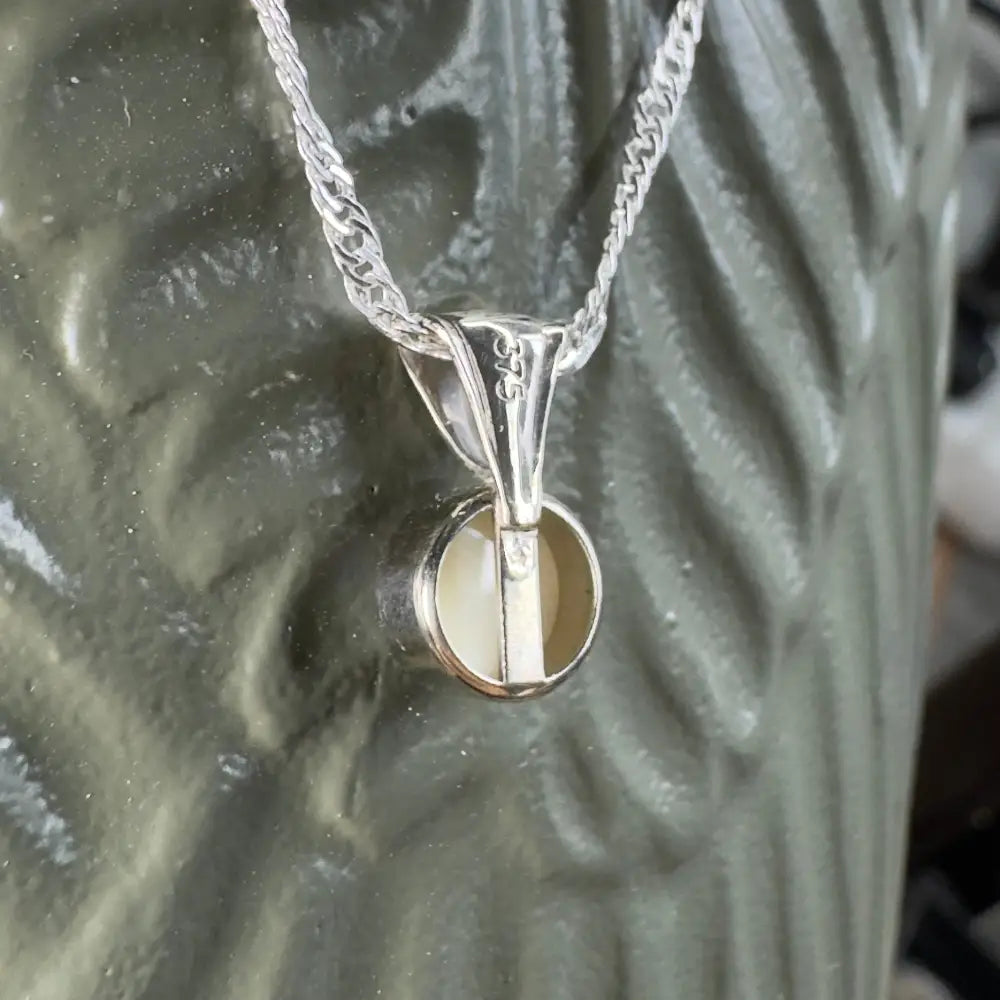 Silver pendant necklace with circular stone.