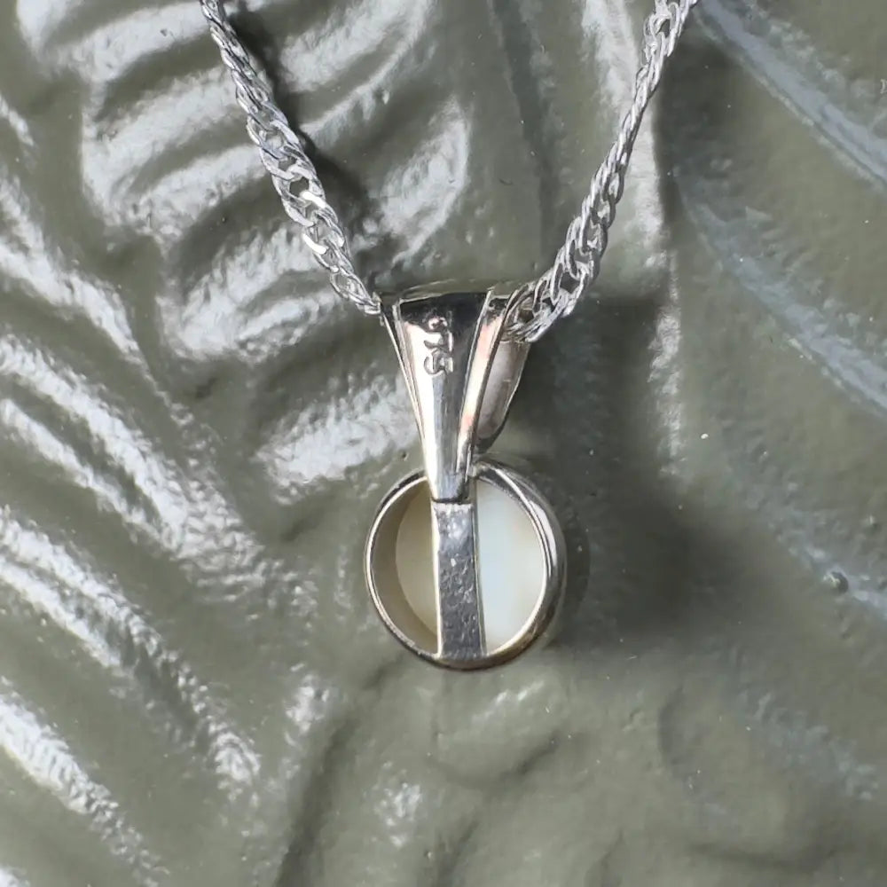 Silver necklace with round, white pendant.