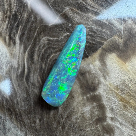 Iridescent blue-green opal cabochon displayed in 1.3ct Hand-Cut Solid Lightning Ridge Semi Black Opal