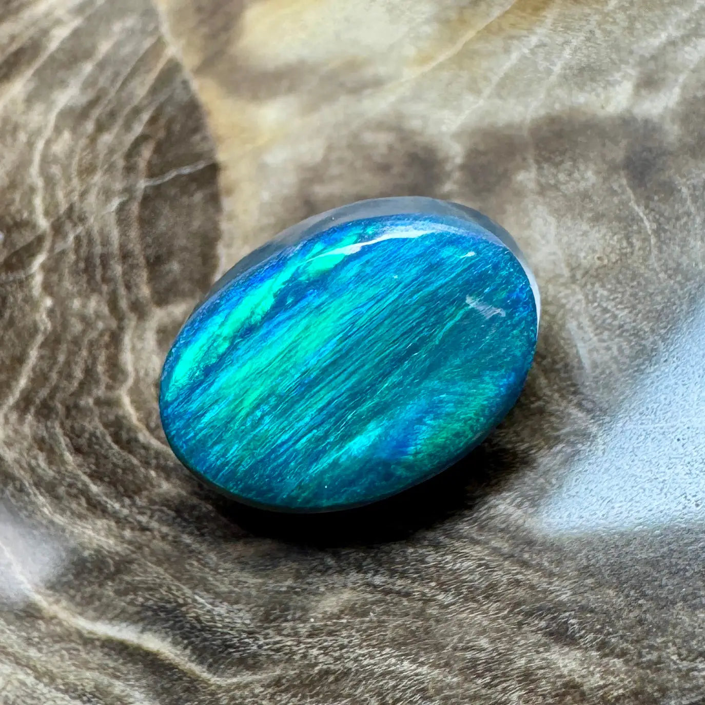 Iridescent blue-green oval gemstone in 1.4ct Hand-Cut Solid Lightning Ridge Semi Black Opal