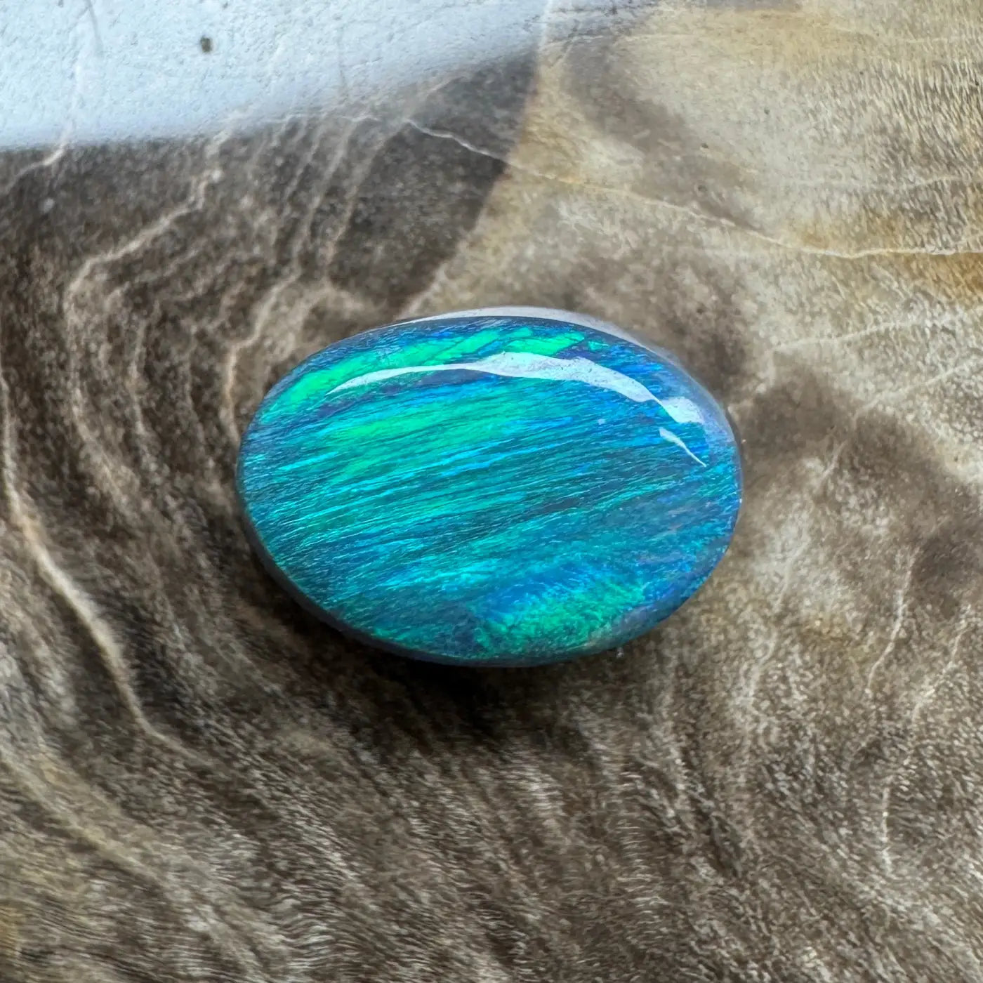 Oval opal gemstone with vibrant blue-green play-of-color in 1.4ct hand-cut Lightning Ridge semi black opal