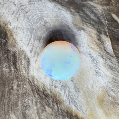 Round opal with blue and orange iridescence.