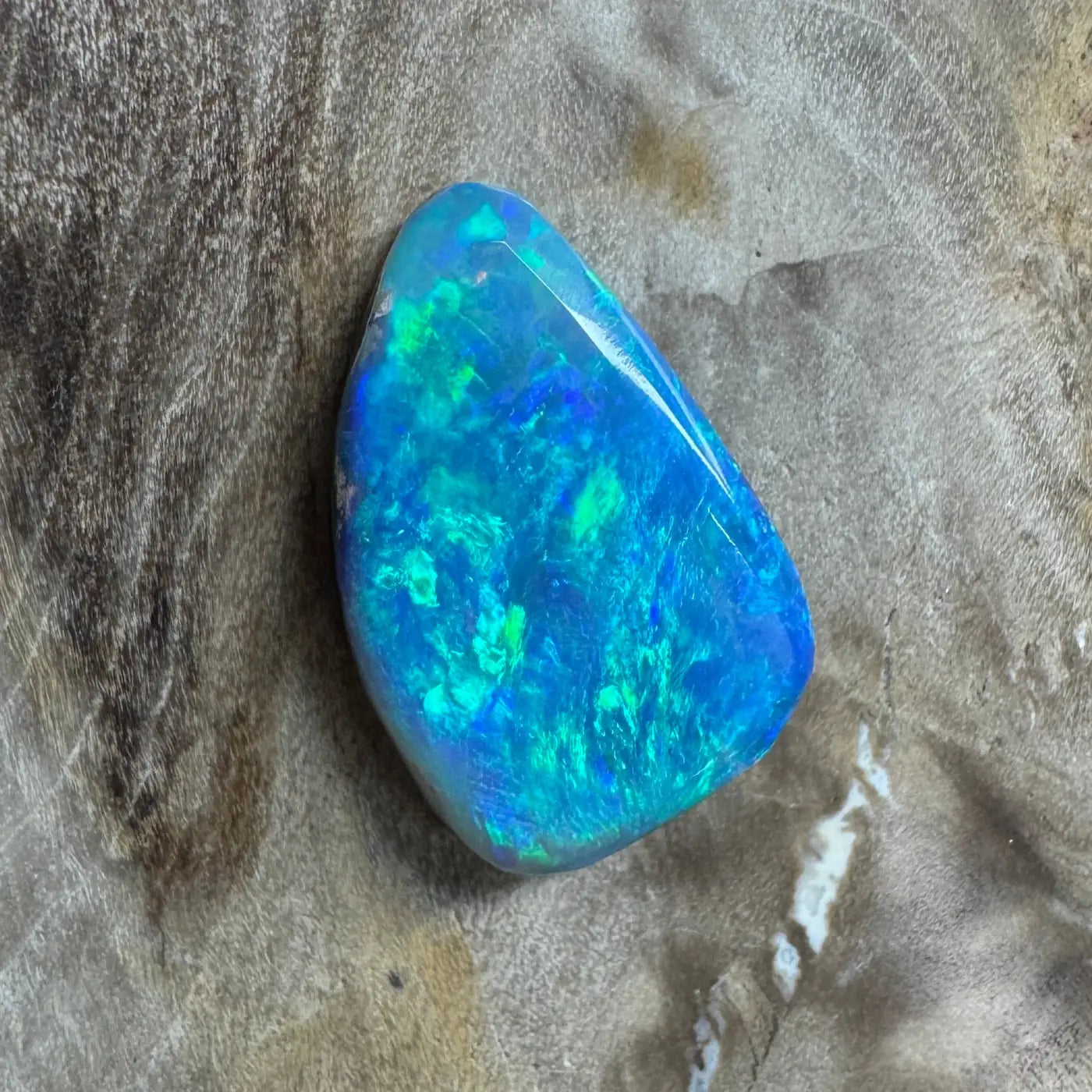 Iridescent blue-green Lightning Ridge semi-black opal gemstone in a product listing