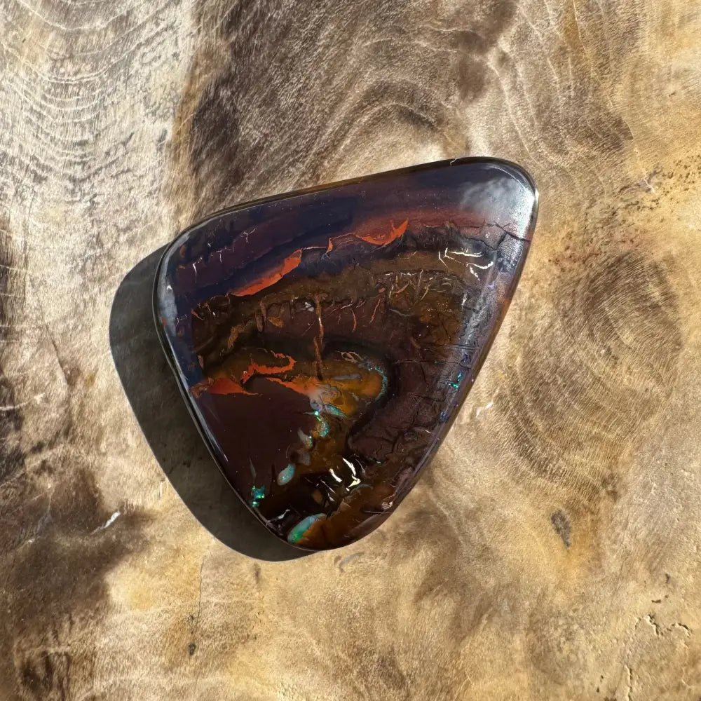 Triangular, polished opal with vibrant color play.