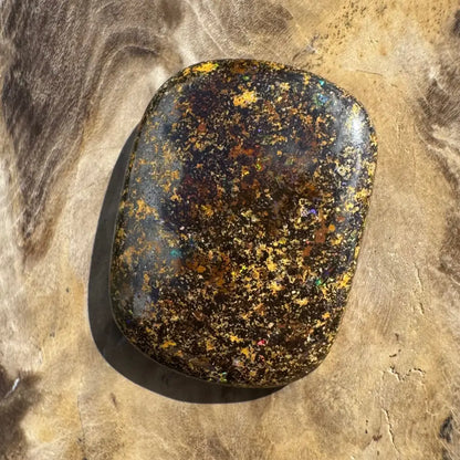 Polished black opal with gold flecks.