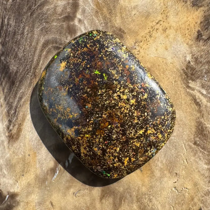 Polished black opal with multicolored flecks.