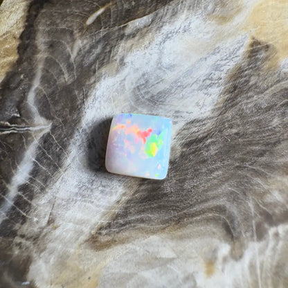 Square opal gemstone with rainbow flashes.