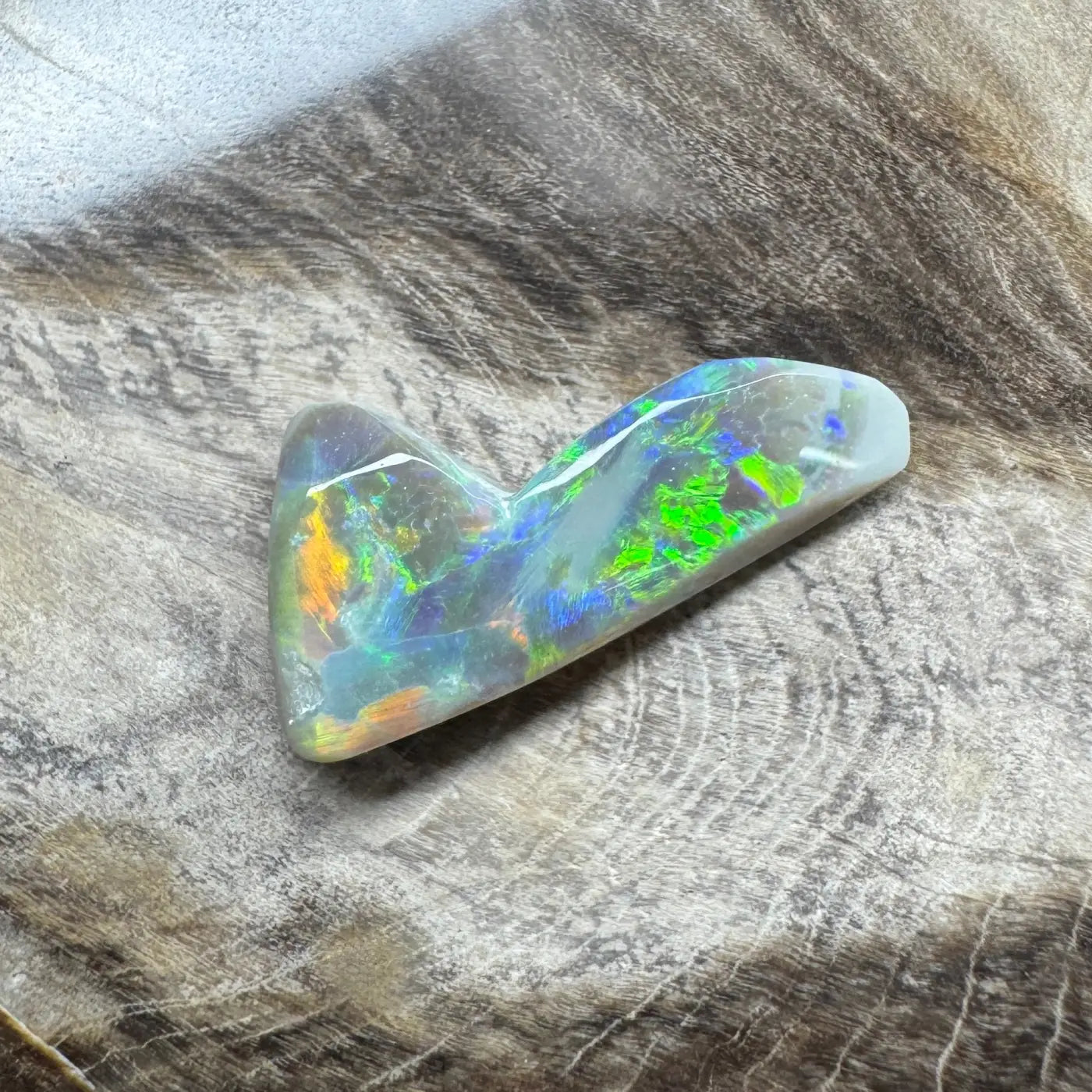 Iridescent opal gemstone in a 2.5 carat hand-cut solid Lightning Ridge semi-black opal display