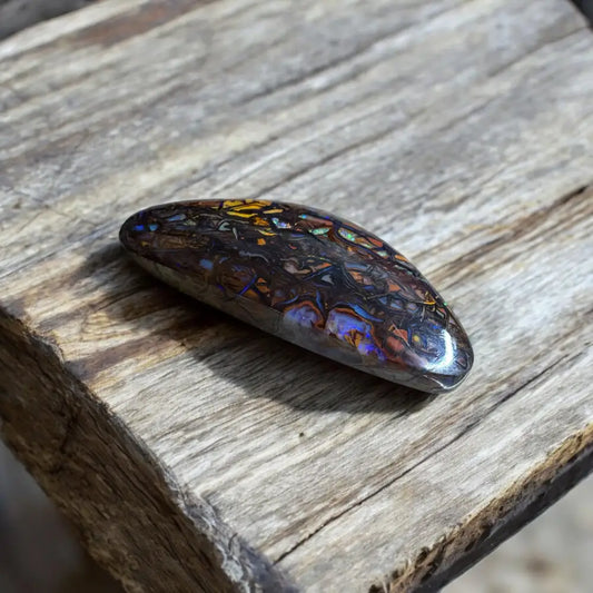 Polished multicolored Queensland Boulder Opal cabochon showcasing vibrant hues and intricate patterns