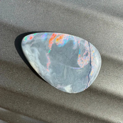 Iridescent black opal cabochon displayed in 5.7 carat Hand-Cut Solid Lightning Ridge Semi Black Opal