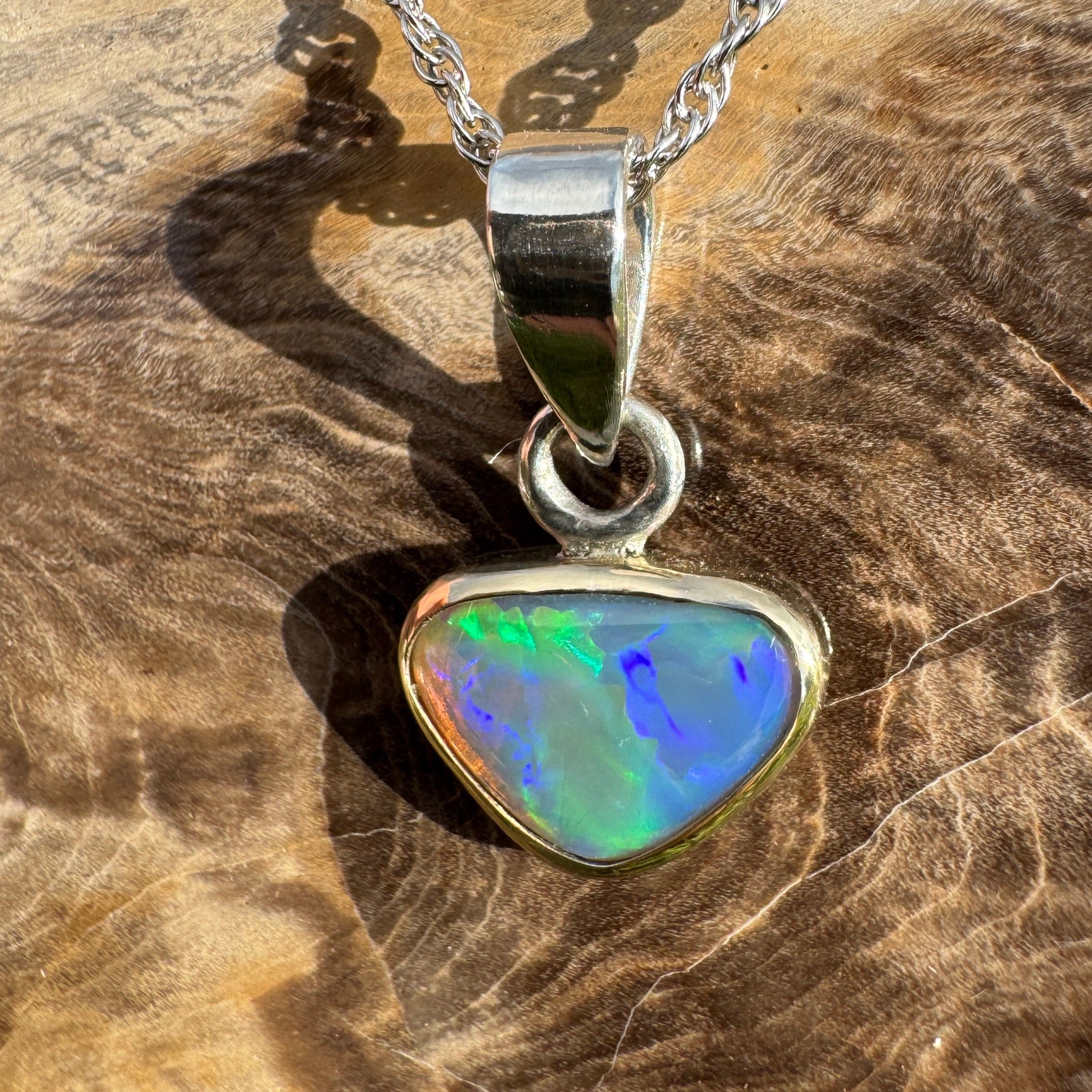 Opal pendant on a silver chain against a wooden background