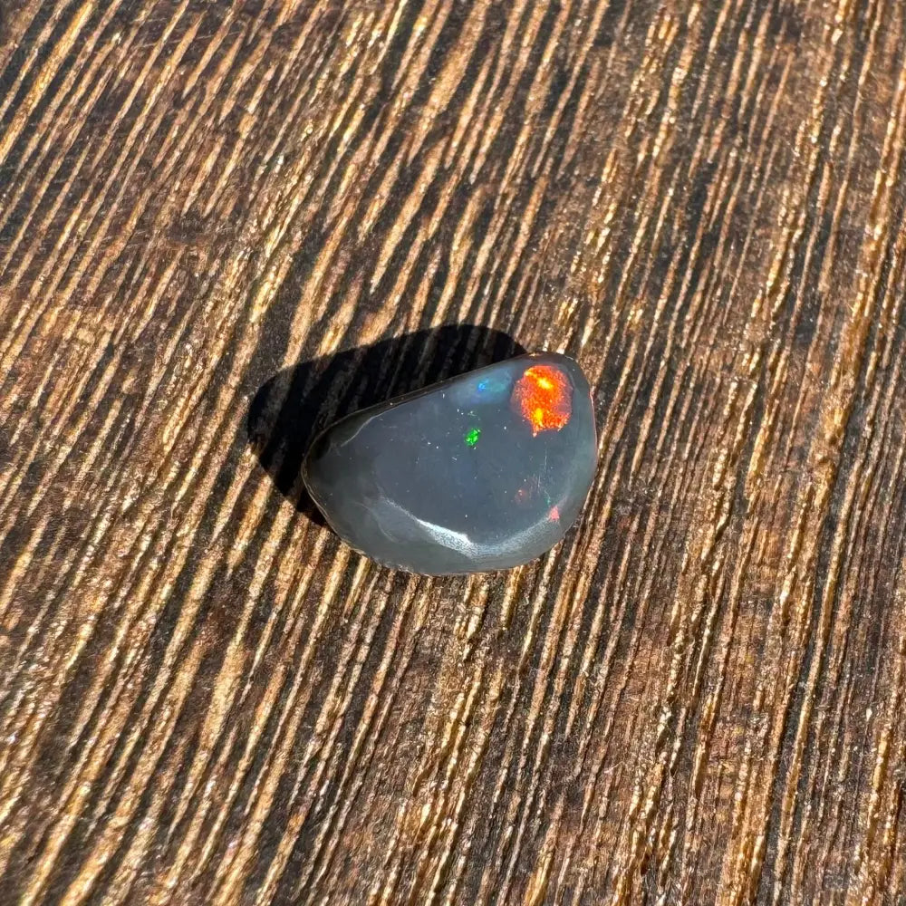 Polished Lightning Ridge black opal with vibrant color flashes in a 1.4 carat solid hand-cut setting