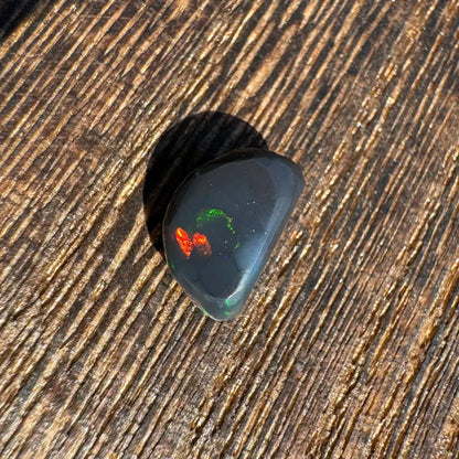 Polished Lightning Ridge black opal with red and green flashes, 1.4 carats, hand-cut