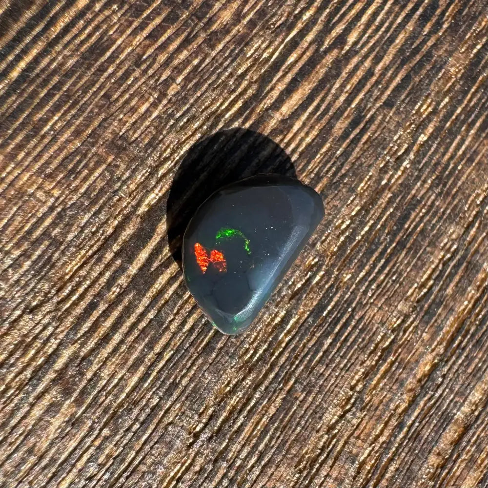 Polished Lightning Ridge black opal with vibrant red and green flashes, 1.4 carats