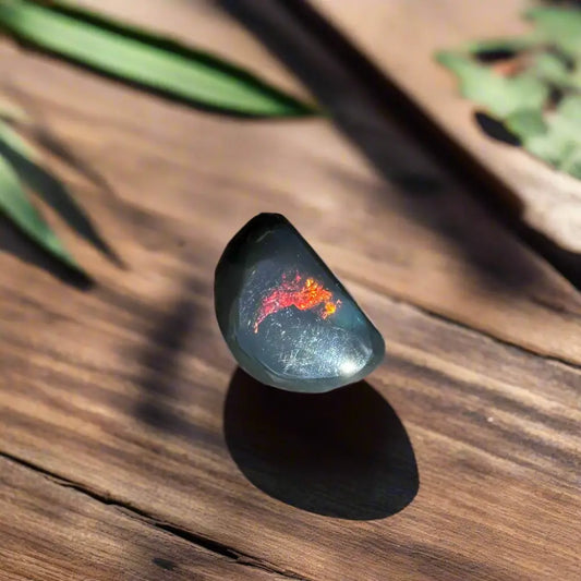 Black opal gemstone with red and orange fire from Lightning Ridge featured in a hand-cut 1.4-carat product