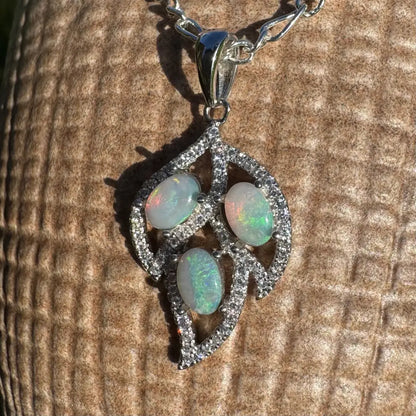 Silver leaf pendant featuring three opals, diamond accents, and handcrafted sterling silver