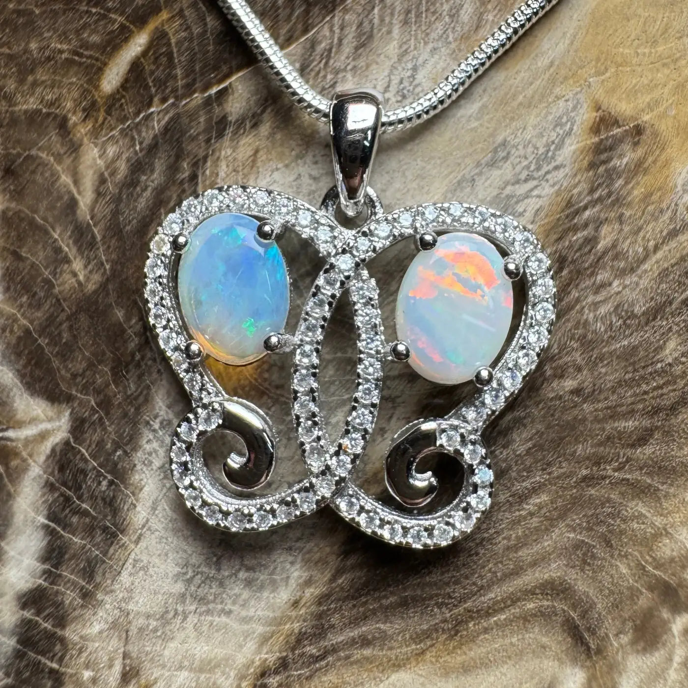 Butterfly-shaped pendant with Coober Pedy opal, Lightning Ridge opal, and cubic zirconia in sterling silver
