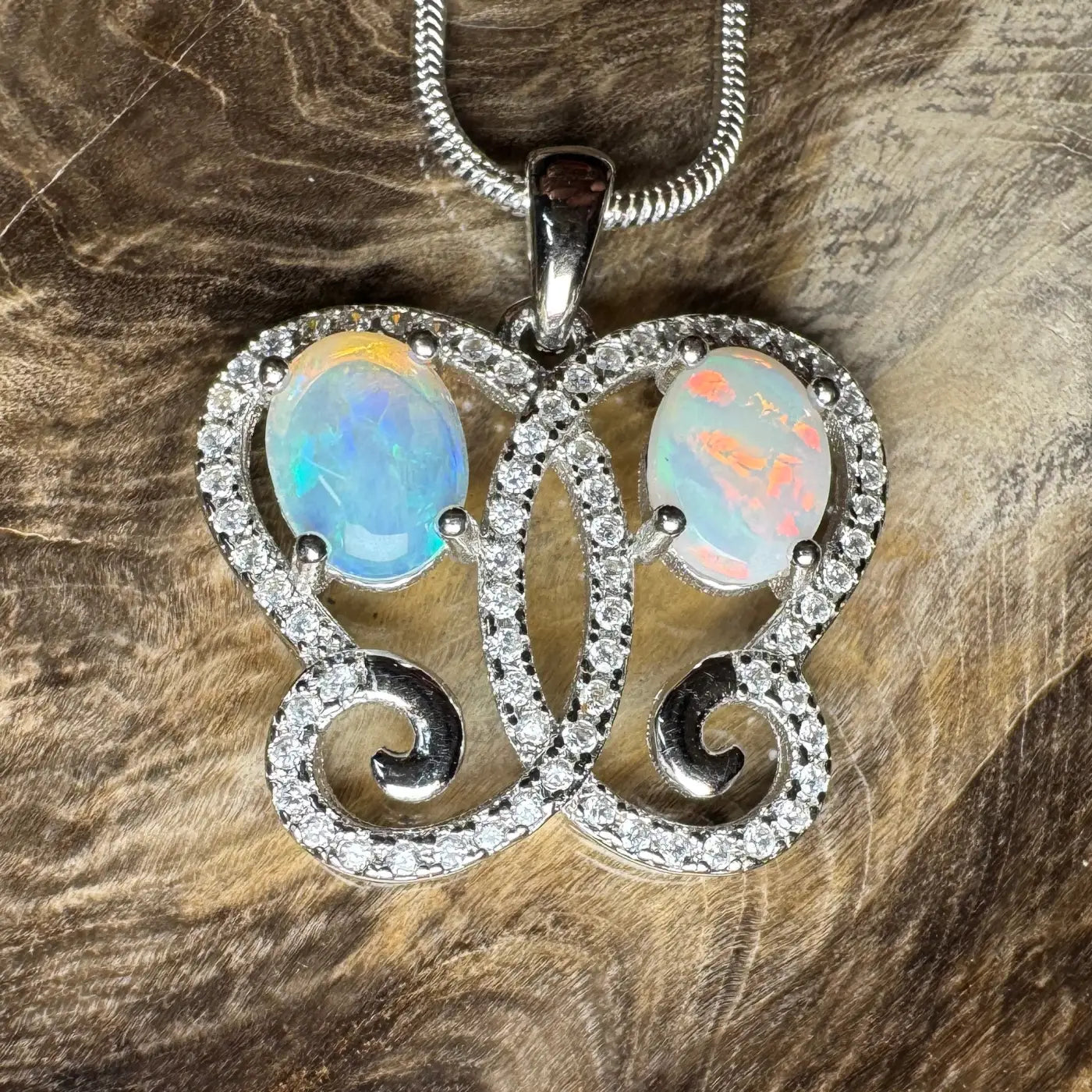 Butterfly-shaped pendant featuring Coober Pedy opal, Lightning Ridge opal, and diamonds
